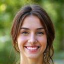 Portrait of Emily R., a smiling young woman, with a blurred natural background.